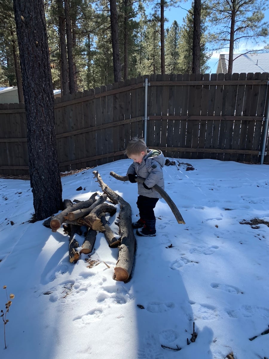 kid playing with snow covered wood