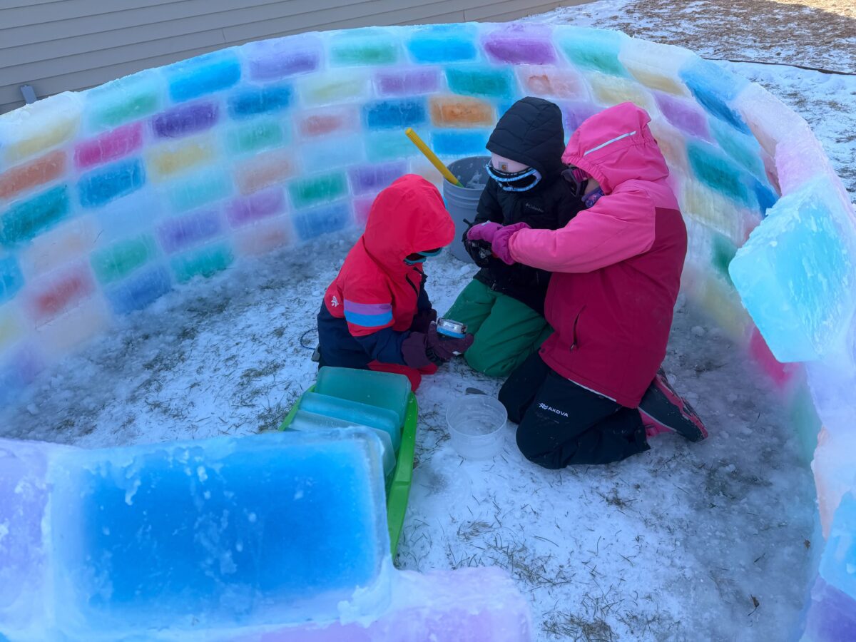 Three kids play inside a colored ice fort doing frozen bubbles