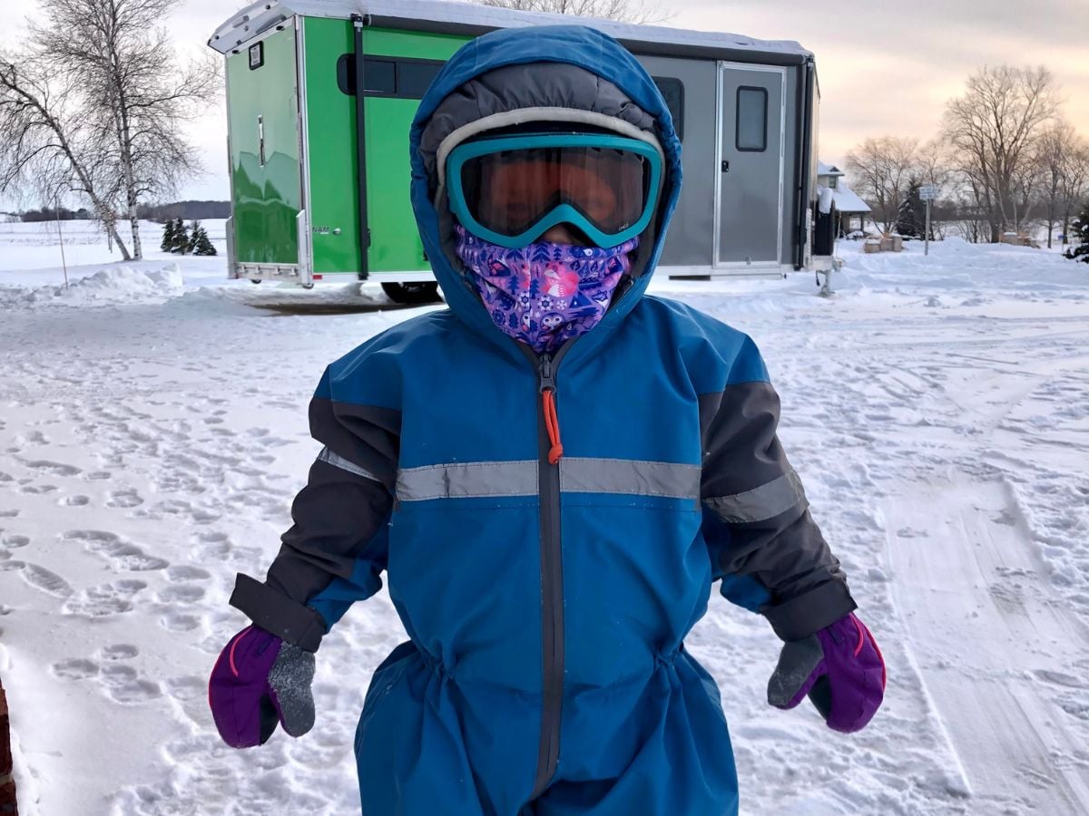 A child is all bundled in a snowsuit with goggles on a frigid winter day.