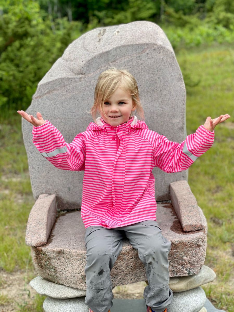 A girl sits in a rock chair in a rain jacket