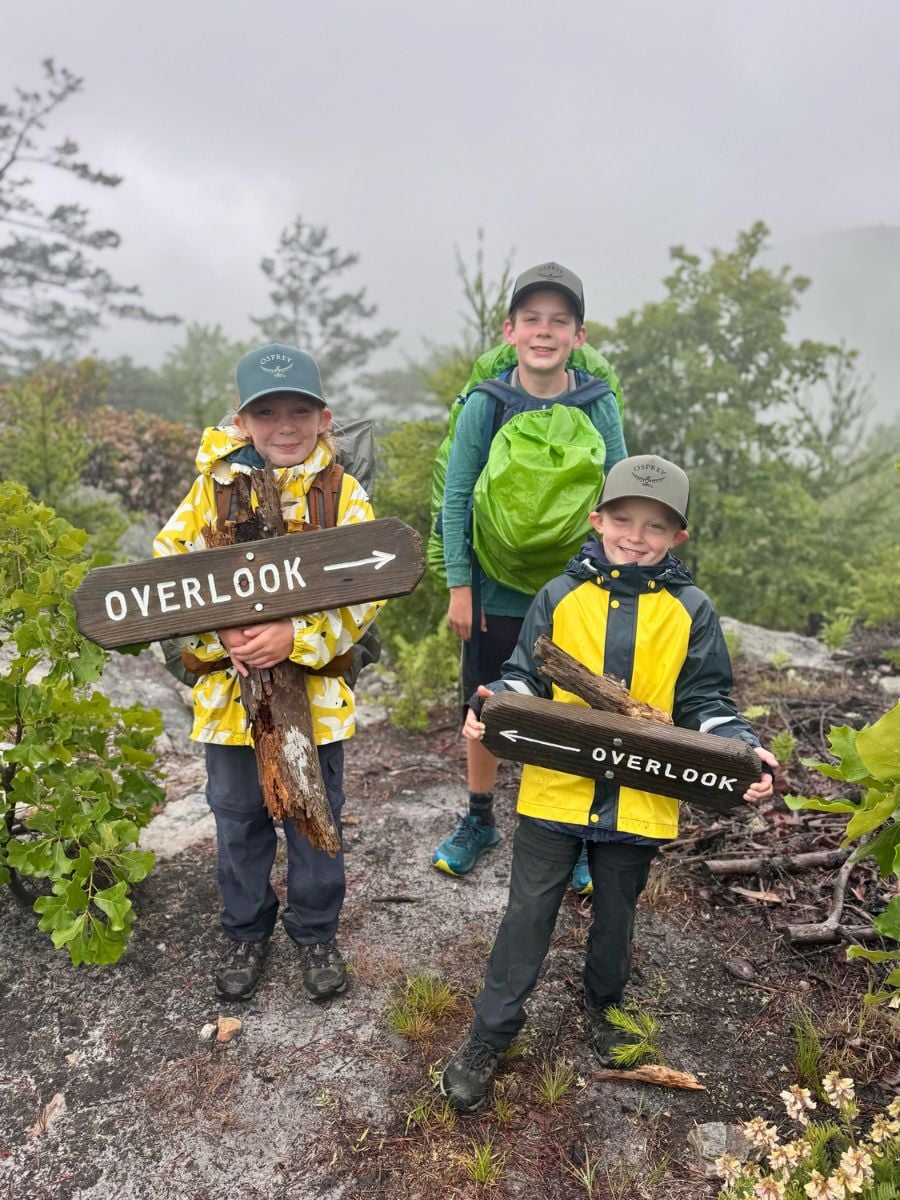 Three boys hike in rain gear