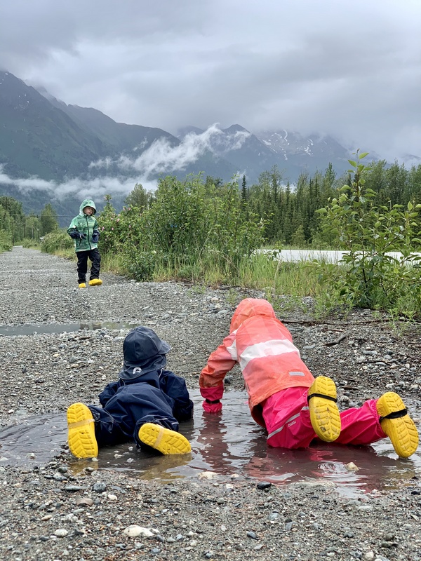 Kids laying in a puddle in the mountains.