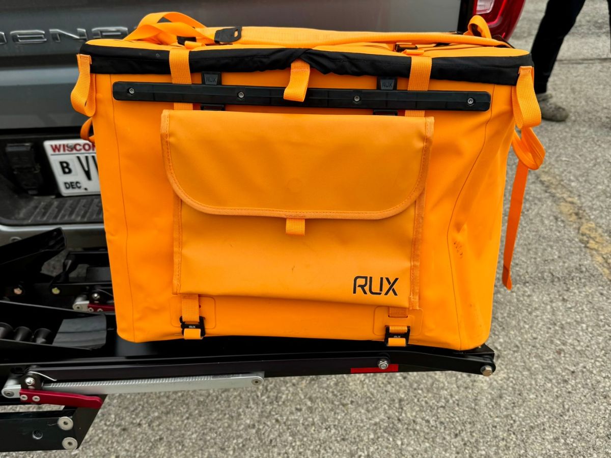 CampinggiftguideRuxGearBox An orange Rux gear box sits on a bike rack.