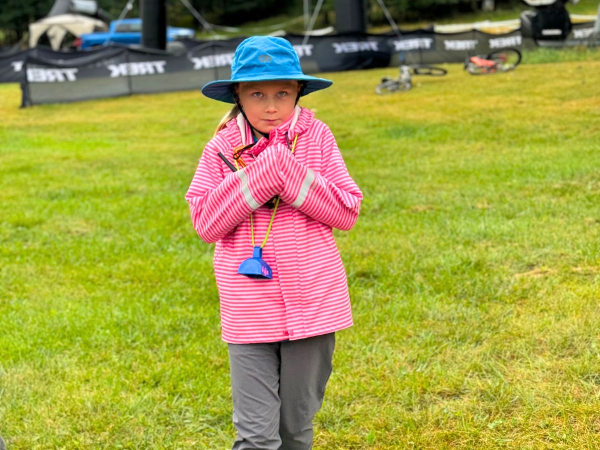 raingearreaimaorhat A young girl with a blue rain hat and pink rain jacket walks toward the camera.
