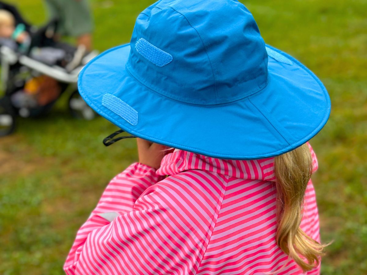 raingearreimaorhat2 The back of a child with a blue rain hat and pink rain jacket.