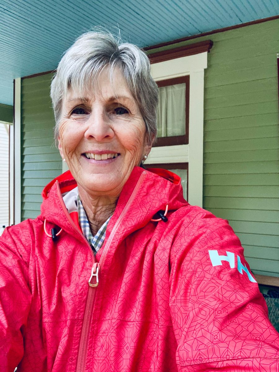A woman smiles in a selfie, wearing a brightly colored Helly Hansen Loke Rain Jacket.