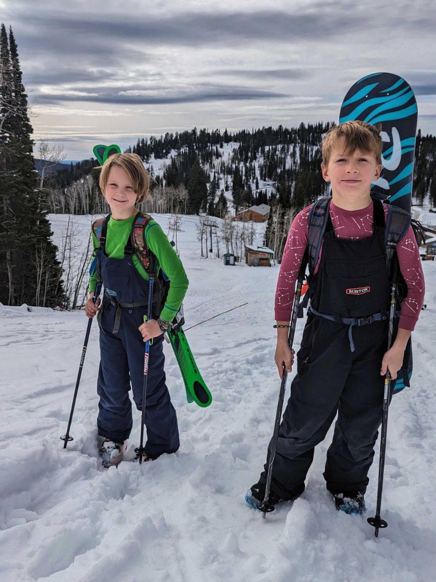Grit2 Two children hike uphill with snowboards in the winter.