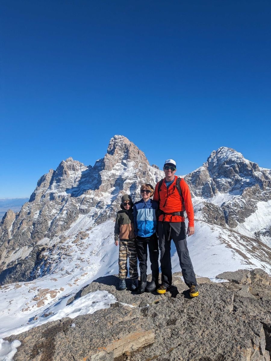 Grit4 A father on a mountain peak with two children.
