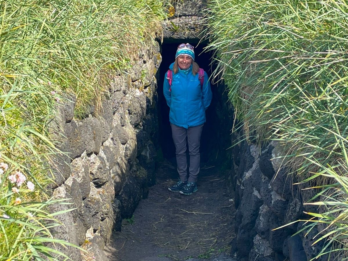 hikingpantsprana A woman with a blue jacket and gray pants stands in an underground entrance.