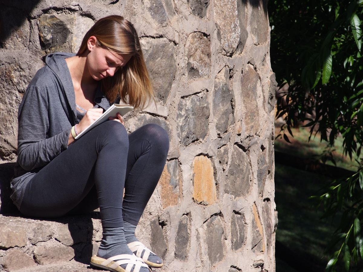 A woman writes in a journal outdoors.