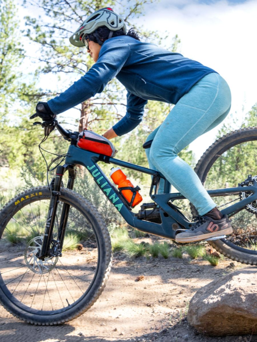 GG_OutdoorWomen2025Life1 A Woman mountain biking wearing the Title Nine Crash Fleece Lined Tights.