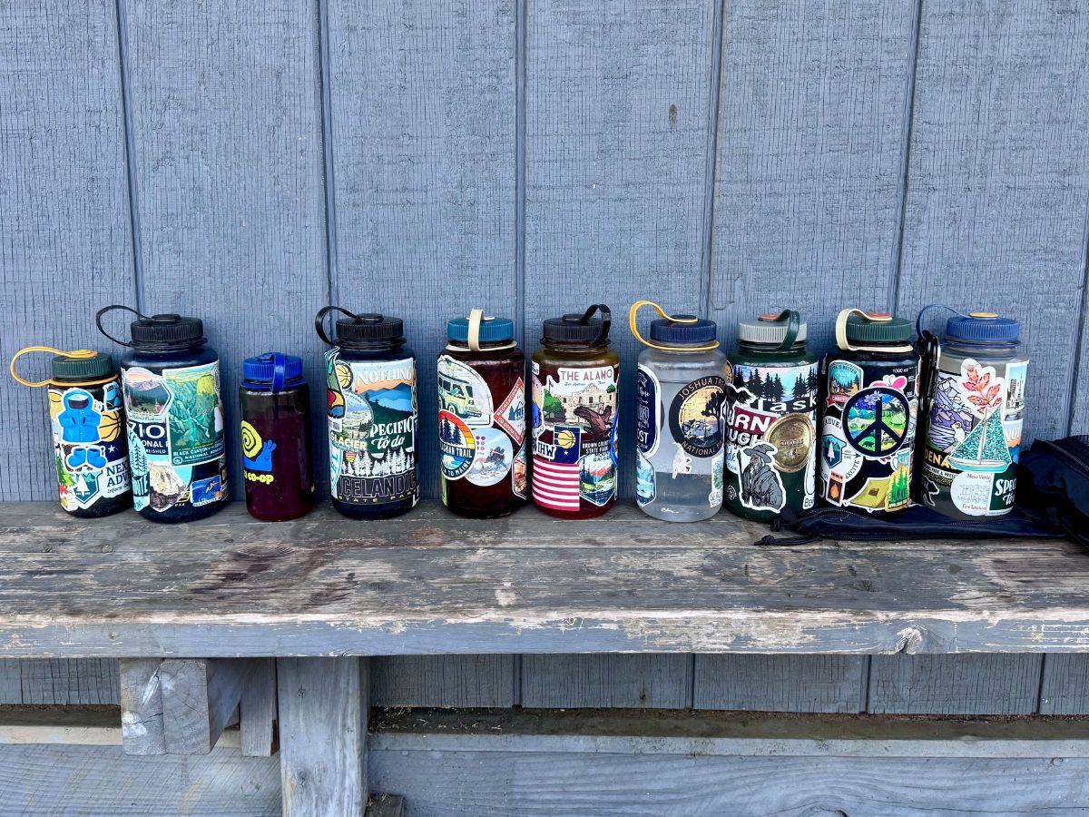 Ten stickered Nalgene bottles sit on a bench.