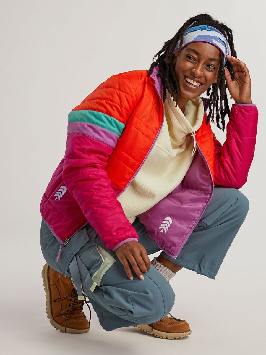 WomenOwnedGear_TownHallLifestyle A woman with dreads and a cool headband squats down, wearing a red jacket.