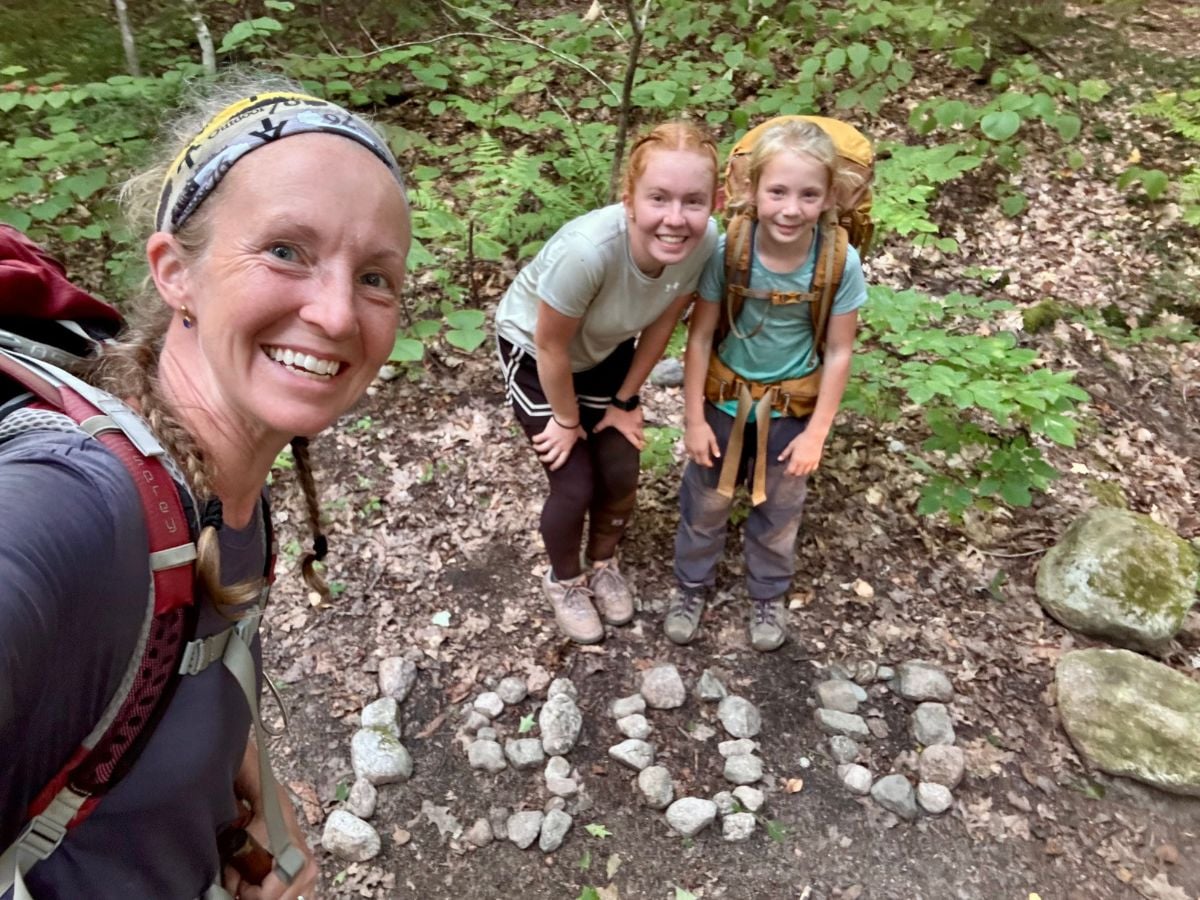 A mom and two daughters stand near "1900" rock pile on the Appalachian trail.