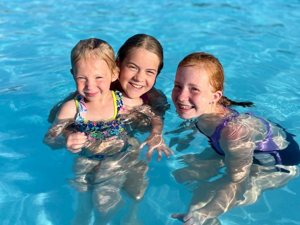 Three girls enjoy a swimming pool.