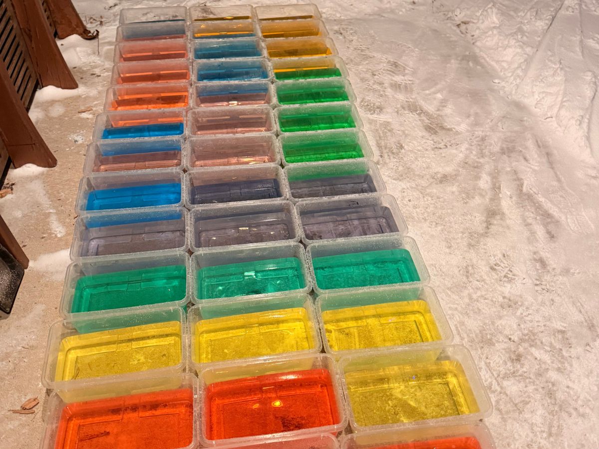 BuildanIceIgloo (5) Containers of colored water sit on a concrete patio.