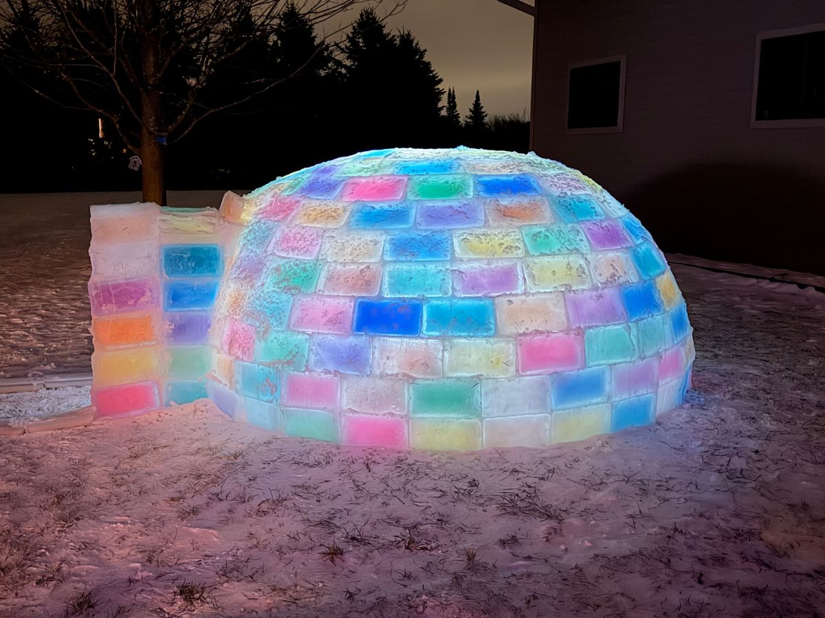A colorful ice igloos glows in the night.