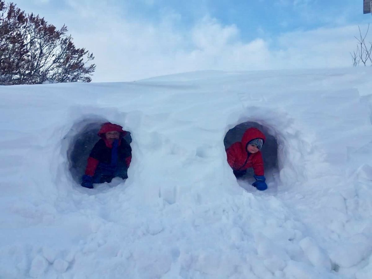 Buildaniceigloo16 Two kids peek out of a snow for tunnel.