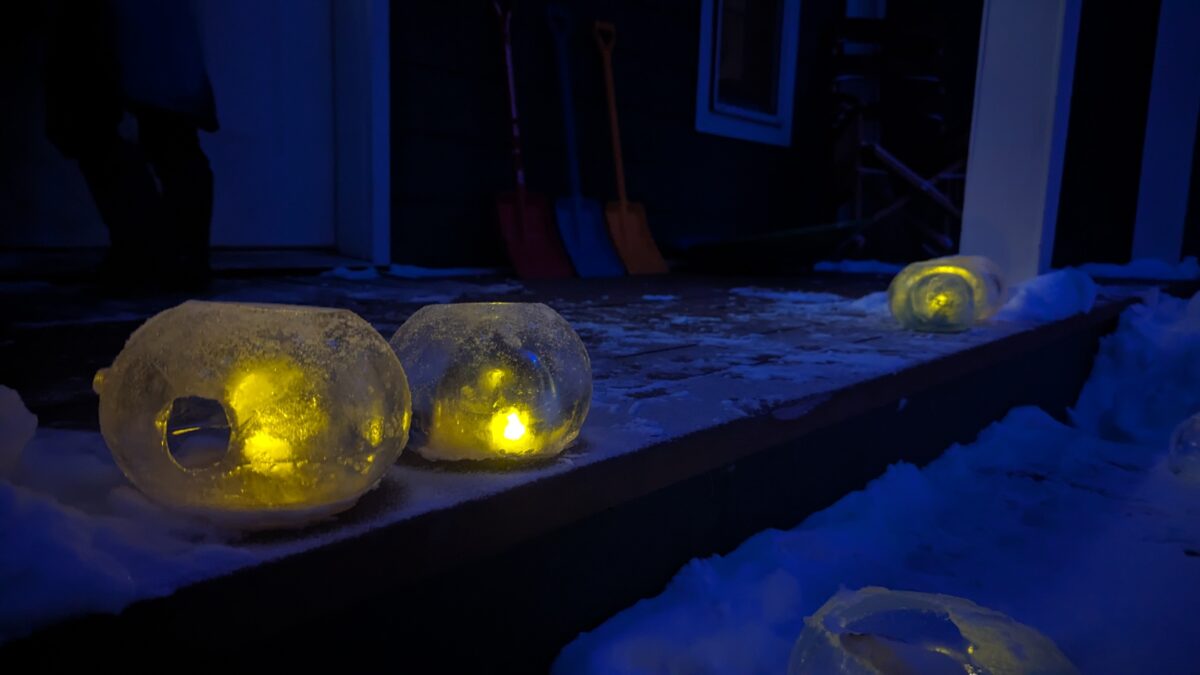 A frozen ice ball on a porch with a light inside.