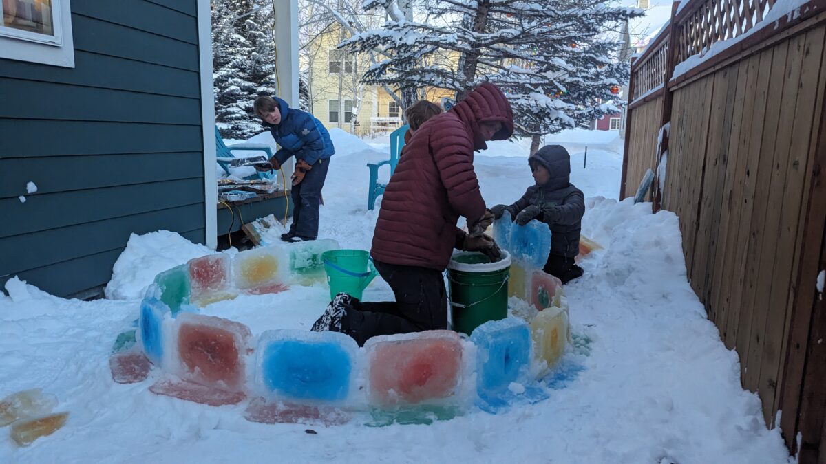 A dad and kids assembling an ice igloo.