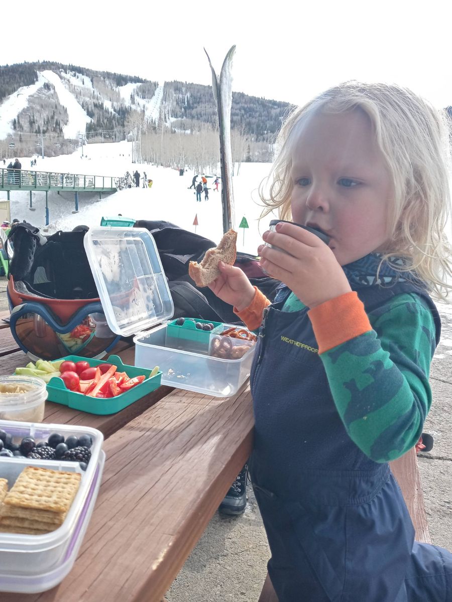 SkiFood2 A child eats lunch at a ski area picnic table-.