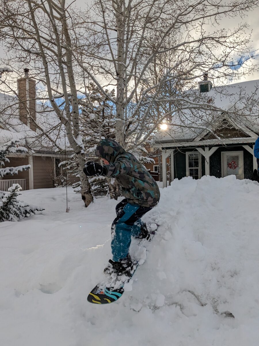 a kid snowboarding in his front yard.