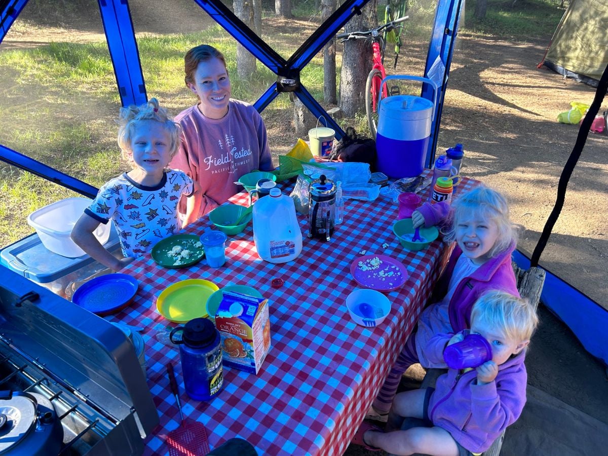 Family eating breakfast camping at a picnic table