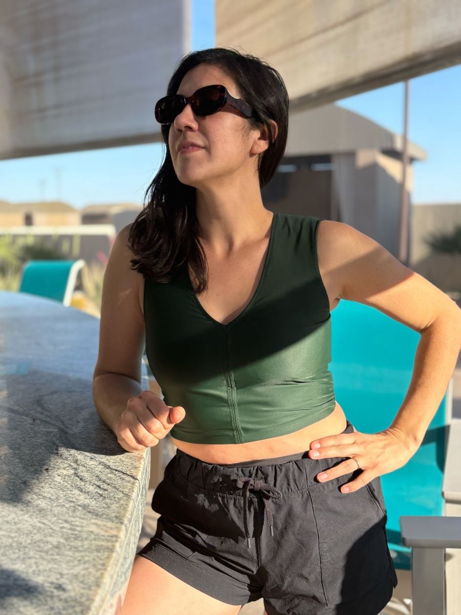 A Woman in a green tankini stands at a counter.