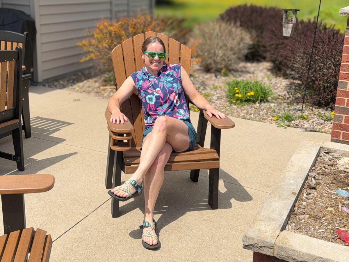 t9sunandswim_9 A woman with sunglasses and a floral sun shirt sits in a patio chair.