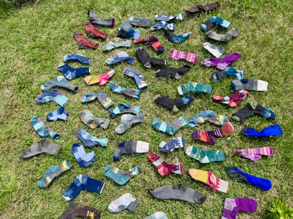 Dozens of wool socks are laid out to dry on grass.