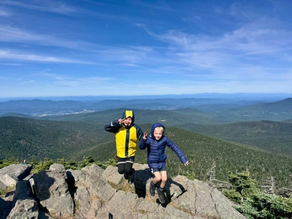 Two young boys jump for joy on top of Mount Killington in Vermont.