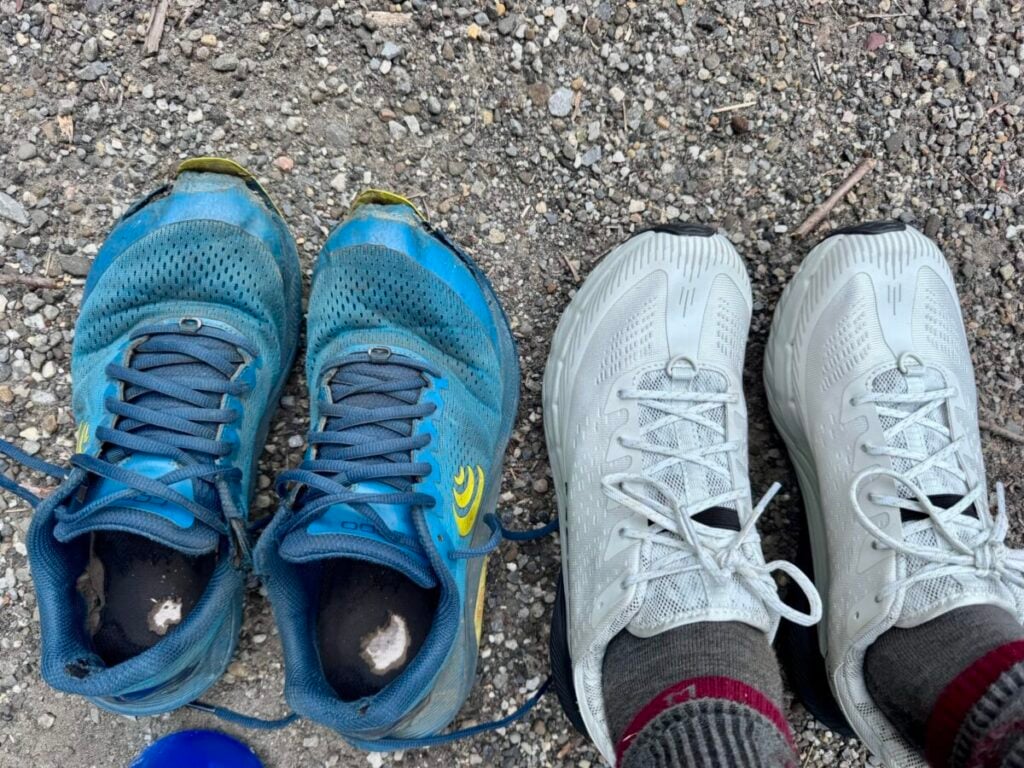 Two pairs of hiking shoes next to each other, one well worn and the other fresh and new.