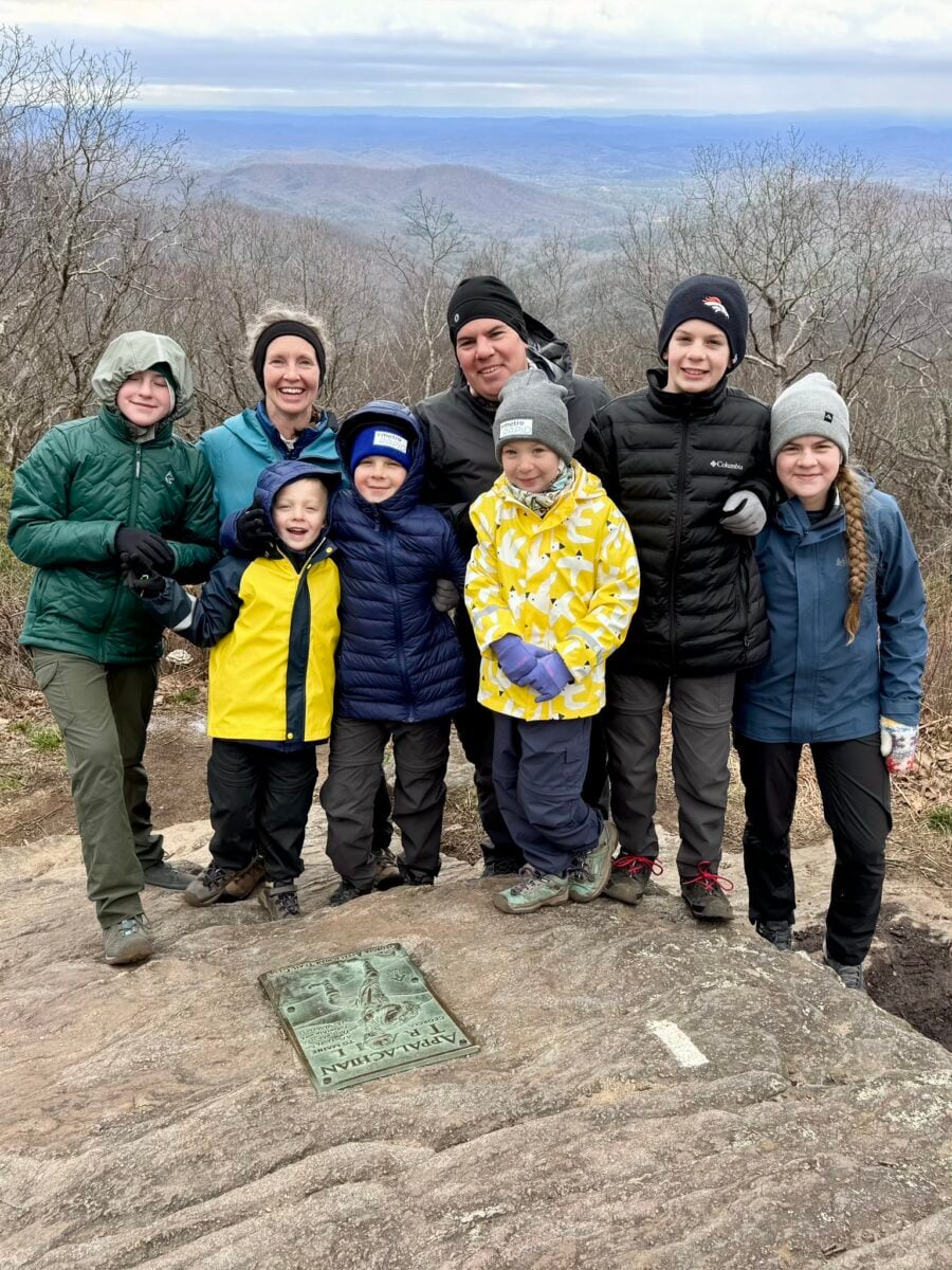 A large family poses with the marker at the Southern Terminus of the Appalachian Trail on Springer Mountain.