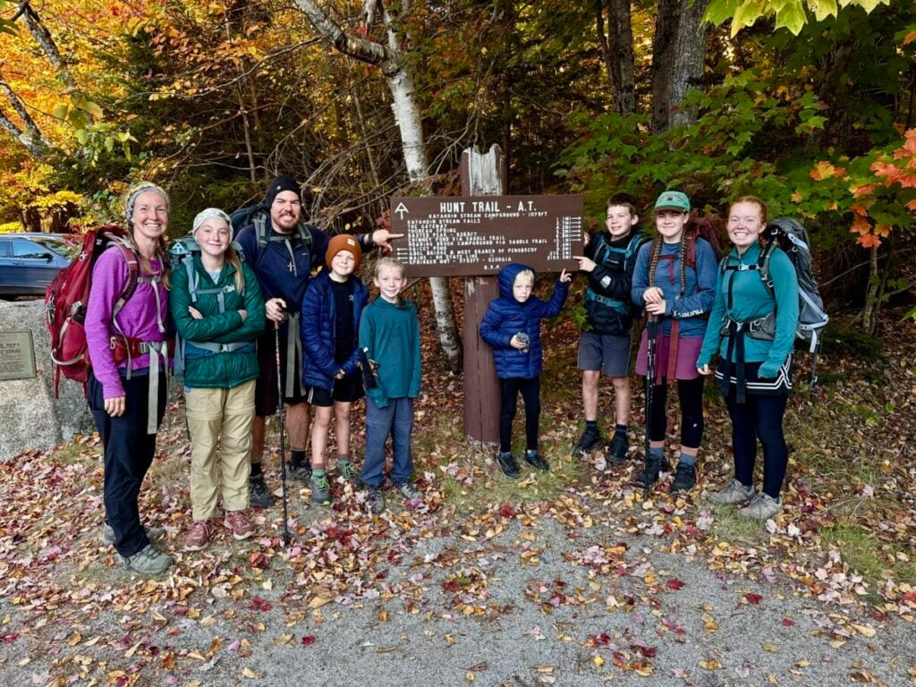 Clothing for a family thru hike. A large family stands at the base of Mount Katahdin in Maine.