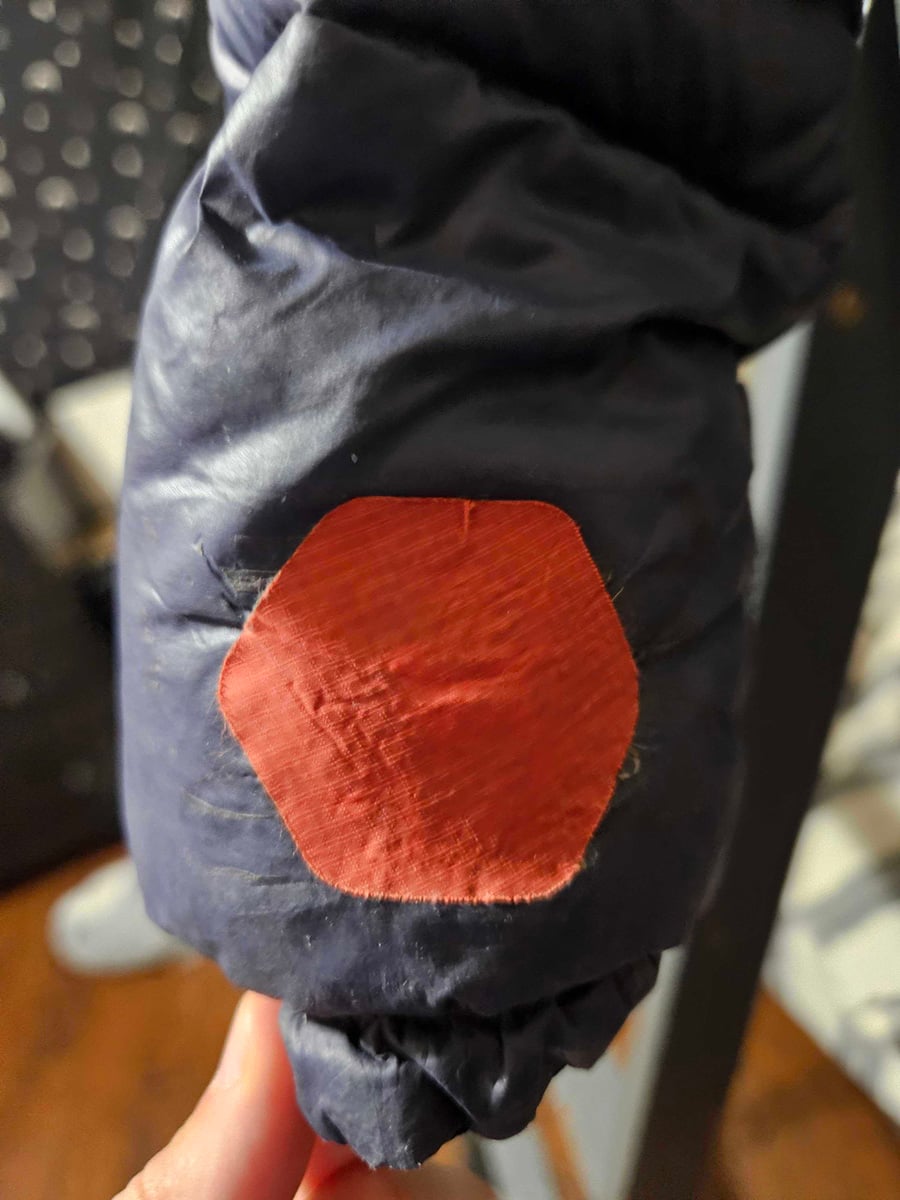 Blue jacket arm with a red hexagonal patch.