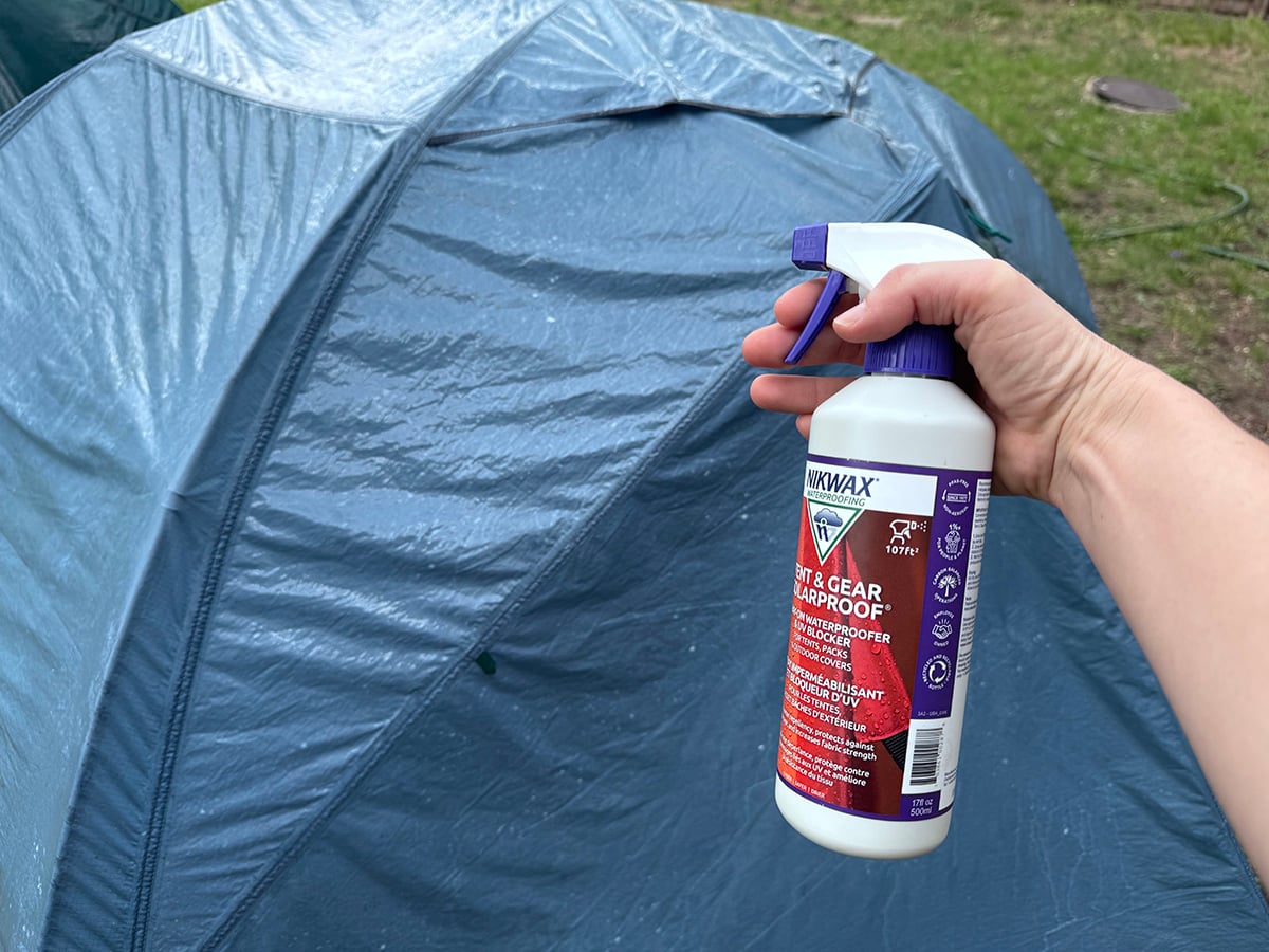 Nikwax DWR spray being used to re-waterproof a blue tent.