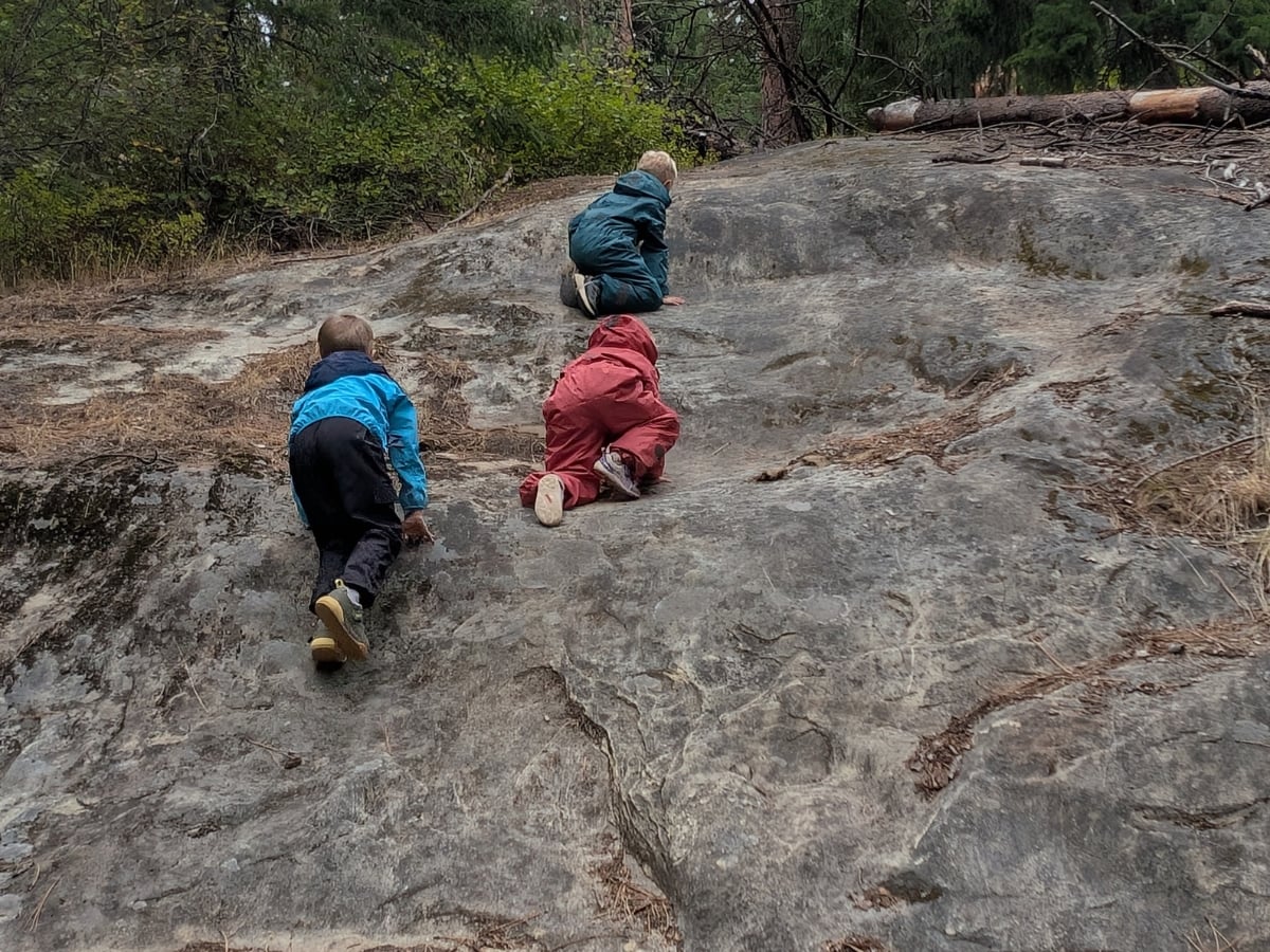 Reima Fall Hiking horizontal 15 three kids climbing up a rock face in Reima fall hiking gear