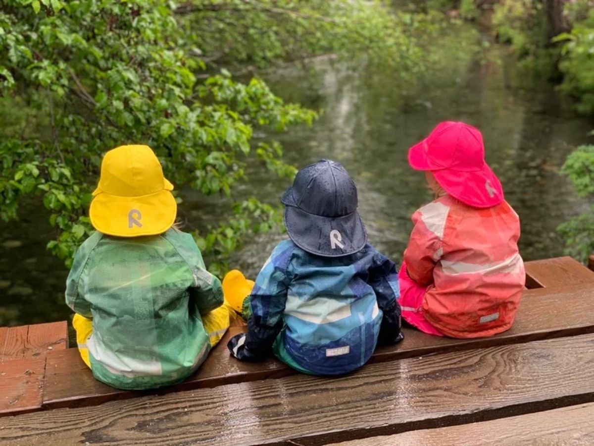 ReimaRainRainyhat Three children face away wearing Reima Rainy Rain Hats.