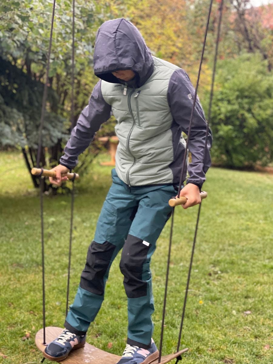 A boy on a standing swing, dressed in Reima fall gear.