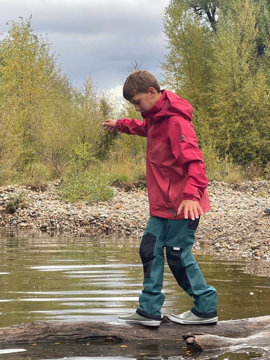 A boy balances on log over a creek.
