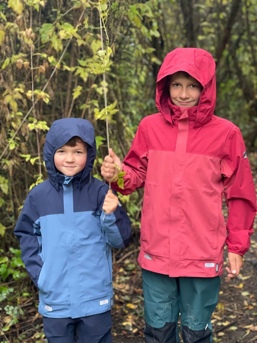 Two boys in rain jackets smiling at the camera.
